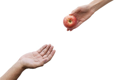 person handing an apple to another person demonstrating the Law of Reciprocity